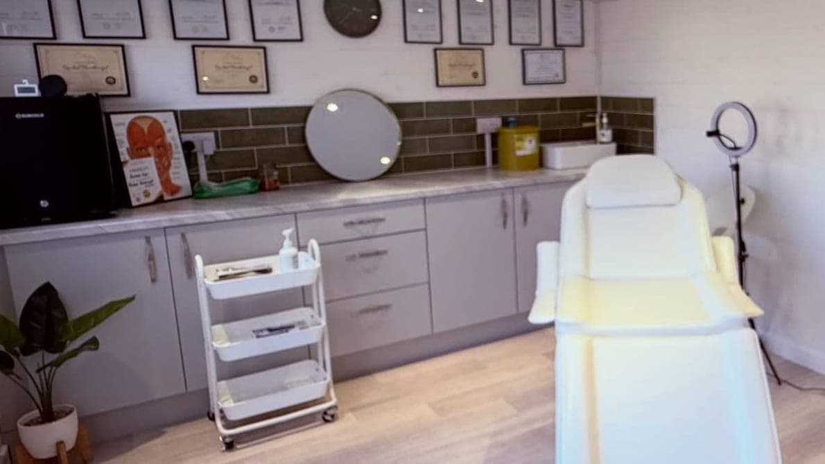 The treatment chair and ring light in Rachel's treatment room, beside the counter and a trolley of supplies